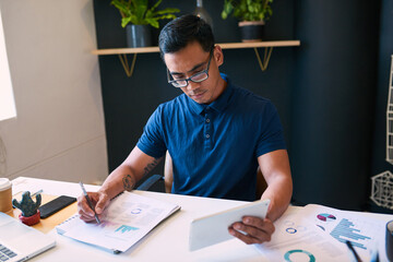 A businessman tracks data with graphs and analyses looking at his digital tablet