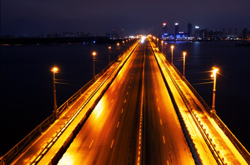 Fototapeta na wymiar Bridge over the river. Night industrial landscape. Drone view.