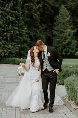 View of bride and groom walking in park