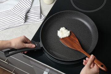 Woman cooking with coconut oil on induction stove, closeup