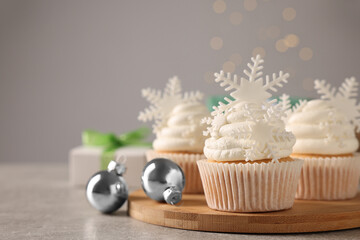Tasty Christmas cupcakes with snowflakes on grey table. Space for text