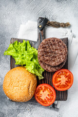 Fried cutlet for burger with vegetables and spices on wooden board. White background. Top view