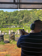 Man firing pistol at target in outdoor shooting range