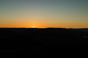 Naklejka na ściany i meble Sunset sky with silhouetted hills