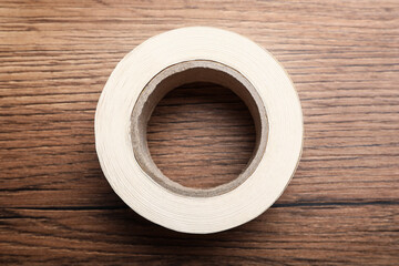 Roll of adhesive tape on wooden background, top view
