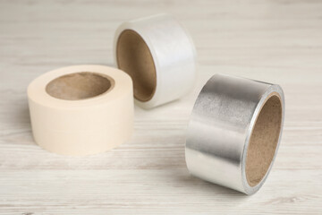 Three different rolls of adhesive tape on wooden table