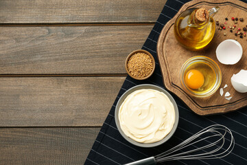 Bowl with fresh mayonnaise and ingredients on wooden table, top view. Space for text