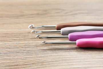 Many crochet hooks on wooden table, closeup