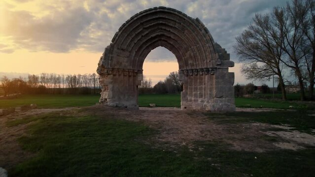 Drone Flying Through a medieval Arch to Reveal a Scenic meadow landscape at dusk in Sasamon, Castile and Leon, Spain. High quality 4k footage
