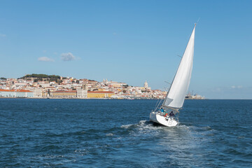 Obraz premium White Yacht sailing in Tagus river with Lisbon cityscape on the background, Portugal