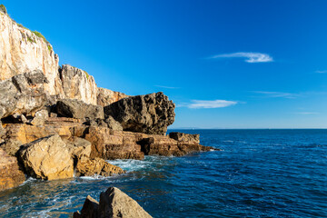 Fototapeta premium Cliffs with fallen rock cliff and formations of Cabo da Guia, next to Cascais and Lighthouse Farol da Guia, Lisbon, Portugal