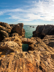 View of the Atlantic Ocean coastline and Pedra da Nau rock, rocky coastal area in Cascais on a sunny day, Portugal