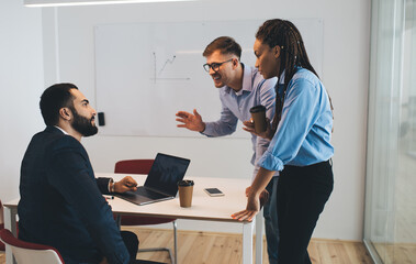 Group of successful male and female colleagues discussing business plan during office brainstorming...