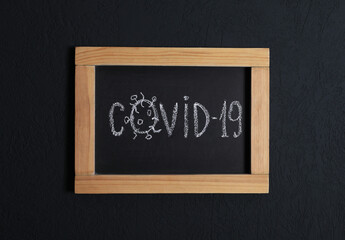 Blackboard with word Covid19 on black background, top view