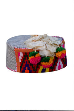 closeup the colorful hand made himachali indian traditional cap with hanging white flowers isolated on white background.