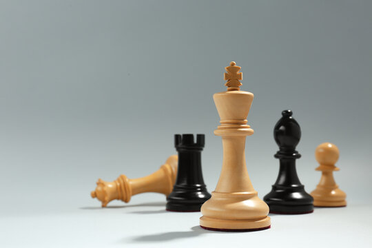 Different chess pieces against light background, focus on white king. Space for text