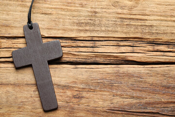 Wooden Christian cross on table, top view. Space for text