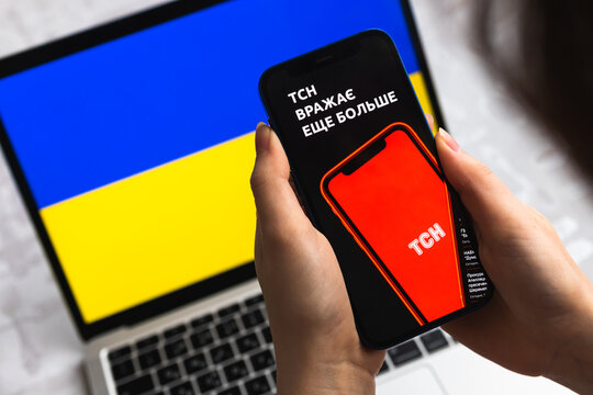 Woman use TSN news app in Ukraine. Mobile phone in hands, flag background photo