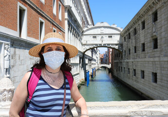Fototapeta na wymiar Pretty woman with mask during lockdown in Venice in Italy and the Brdige of SIGHS in background