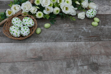 Osterhintergrund: Korb mit Ostereiern und Blumen auf einem Holzhintergrund.