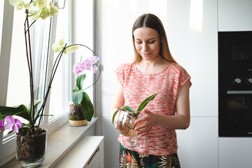 Authentic young woman holding an orchid plant in a glass can with water