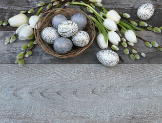 Fototapeta na wymiar Ostereier mit Tulpen und Weidekätzchen auf einem Holzhintergrund.