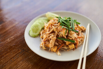 One chicken chow mein coming right up. Closeup shot of Chinese food on a plate on a wooden table.