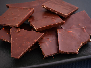 Pieces of broken chocolate on a black plate.
