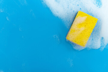 Soap foam. Yellow sponge on a blue background with soapy foam. Place on background for text