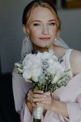  Close-up portrait of a bride in pajamas with a bouquet of white roses