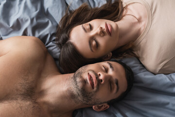 Fototapeta na wymiar Top view of brunette woman lying near shirtless boyfriend on bed.