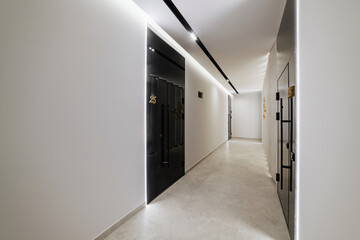 new bright interior of the corridor in the house with black doors and lighting