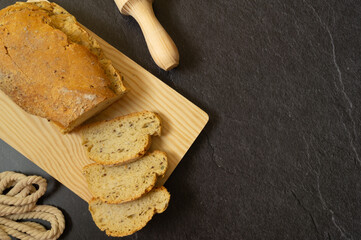 
sourdough bread slices on wooden board, freshly baked homemade, natural ingredients, freshness, flour, top photo, black background, space for text.