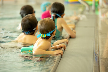 Child, taking swimming lessons in a group of children in indoor pool
