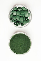 natural additives and superfood. green spirulina algae powder and pills in glass bowls on white background. healthy lifestyle concept. organic food