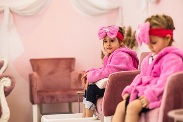 Sweet little girl in children spa center using a foot bath and waiting for her next treatment.