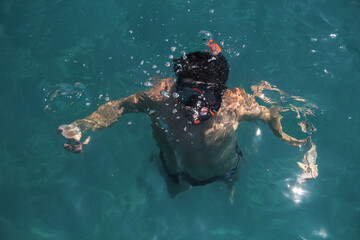 Young man snorkeling in clean water on the sea. Top view of the swimmers with, mask and snorkel.