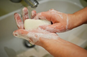 Person washing hands with a soap in bathroom