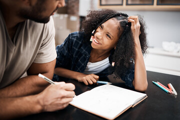 Will break for dad jokes. Shot of a young girl doing a school assignment with her father at home.