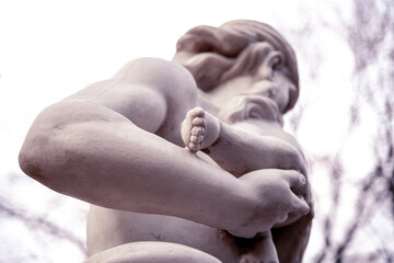 Marble sculpture. A man is holding a baby in his arms.