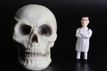 miniature figurine of a doctor with a giant human skull