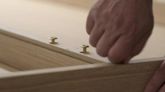 Trabajador aprieta un tornillo en el montaje de una mesa
