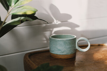 Stylish cup in sunlight on rustic background. Morning coffee aesthetics
