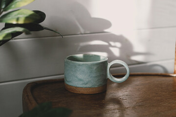 Stylish cup in sunlight and shadow on rustic background. Morning coffee aesthetics