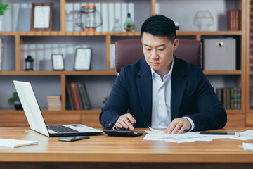 Serious and pensive Asian businessman, boss, working in a classic office, thinking about a solution