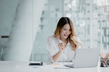 A businesswoman is checking company financial documents and using a laptop to talk to the chief financial officer through a messaging program. Concept of company financial management.