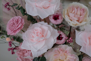 Beautiful bouquet of peonies and pink roses on the table. In the background is the interior of a modern white kitchen. Concept of home comfort.