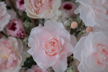 Beautiful bouquet of peonies and pink roses on the table. In the background is the interior of a modern white kitchen. Concept of home comfort.