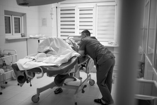 Only A Woman Who Has Given Birth Feeds. Her Baby And Her Husband Came Into The Ward, They Are Watching The Baby Together