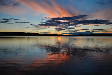 
Colourful sunset over the Umbukta lake in Norway. Orange, red, blue colors in Nordic sky reflecting in the water